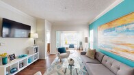 Located at 1013 Madison Place Cir in Kernersville, NC, this single-floor residence offers a thoughtfully designed layout with a cohesive coastal-inspired color palette throughout. The living area serves as the heart of the home, featuring warm hardwood-style flooring, crown molding, and a bold teal accent wall that adds a striking pop of color. Natural light flows in through a large sliding glass door, creating a bright and welcoming atmosphere. The space is versatile, accommodating both a seating and a separate sitting or den area.

The kitchen is equipped with white cabinetry, a black appliance suite including a refrigerator and range, and a generous wraparound breakfast bar with pendant lighting overhead — ideal for casual dining or entertaining. A convenient pantry closet provides ample storage.

Two bedrooms offer comfortable retreats, each with plush carpeting, natural light from well-positioned windows, and access to closet space. The primary bedroom features a walk-in closet and a calming accent wall. Both bathrooms are finished with wood-style flooring, white vanities with stone-look countertops, and a tub-shower combination with tile surround, delivering a clean and functional design throughout.