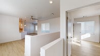 This well-appointed single-floor residence showcases a clean, contemporary design throughout. Light wood-tone flooring flows seamlessly across the open living areas, creating a warm and cohesive aesthetic. The spacious main living area benefits from multiple windows dressed with horizontal blinds, allowing natural light to fill the space, while a ceiling fan with brass accents adds a modern yet functional touch.

The kitchen is thoughtfully designed with crisp white shaker-style cabinetry, stainless steel appliances including a gas range, over-the-range microwave, and a full-size refrigerator, all set against light wood flooring for a bright, functional workspace.

The bedrooms are generously sized and well-lit, each featuring large windows with outdoor views, light wood flooring, and ceiling fans that enhance comfort and airflow. One bedroom features a row of clerestory windows that invite additional natural light while maintaining privacy.

The bathroom is finished with large-format gray tile in a walk-in shower enclosed by sleek sliding glass doors, complemented by chrome fixtures and a clean white vanity. The overall design of the space is neutral and move-in ready, presenting a bright, airy ambiance with modern finishes throughout.