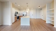 This well-appointed 2-bedroom, 2-bathroom single-floor residence offers a thoughtfully designed open-concept layout. The combined kitchen and living area serves as the heart of the home, featuring durable wood-look flooring that flows seamlessly throughout. The kitchen is outfitted with a large central island with a white quartz countertop and undermount sink, two-tone cabinetry pairing white upper cabinets with warm wood lower cabinets, a tile backsplash, and a full suite of stainless steel appliances including a refrigerator with ice maker, electric range, and over-the-range microwave. Pendant lighting above the island adds a refined touch. The living area is bright and open, with a glass door leading to a private balcony. Both bedrooms feature plush carpeting, ceiling fans, and generous natural light from large windows. Each bedroom is accompanied by a dedicated closet. The two bathrooms are finished with wood-toned vanities, white quartz countertops, backlit mirrors, and luxury vinyl plank flooring. The primary bathroom includes a soaking tub and separate shower, while the secondary bathroom offers a clean, efficient layout. Built-in shelving near the entry adds practical storage to this move-in-ready residence.