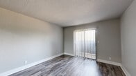 Located at 1703 S Jackson Ave in Tulsa, Oklahoma, this one-bedroom, one-bathroom unit offers a practical and well-appointed single-floor layout. Wood-look plank flooring runs throughout the entire space, lending a cohesive and modern aesthetic to every room.

The combined kitchen and living area forms the heart of the unit. The kitchen features white cabinetry with brushed nickel hardware, a light stone-look countertop with a peninsula, a built-in sink, and black appliances including a refrigerator, electric range, and microwave. An overhead light fixture brightens the space. The adjoining living room is open and airy, with neutral gray walls, clean white baseboards, and a sliding glass door fitted with vertical blinds that fills the room with natural light and provides access to an outdoor area.

The bedroom is a comfortable, well-proportioned room with a ceiling fan with light kit, a window for natural light, and a dedicated closet for storage. Consistent flooring and neutral tones carry through from the rest of the unit.

The bathroom is accessible via a short hallway and includes a full tub-shower combination with white tile surround. Throughout the unit, the clean color palette, updated finishes, and consistent flooring create a cohesive, move-in-ready living environment.