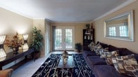 This single-story residence at 2200 S Gessner Rd in Houston, Texas, offers a thoughtfully designed layout that balances comfort and functionality. The living room serves as the heart of the home, featuring crown molding, tile flooring, and a set of French doors that flood the space with natural light and provide direct access to an outdoor patio. A dedicated dining area sits adjacent to the living space, highlighted by a pendant light fixture and crown molding detail, creating an intimate setting for meals. The kitchen is efficiently designed with white cabinetry, white appliances including a range, microwave, and refrigerator, and clean tile flooring that adds a bright, airy feel. The bedroom offers warm hardwood-style flooring, crown molding, and a ceiling fan, providing a serene retreat. The bathroom features a wide vanity with ample counter space, a large mirror with overhead lighting, tile flooring, and a tub-shower combination. Throughout the residence, a cohesive neutral color palette with warm tones creates a calm and inviting ambiance, while consistent crown molding details lend a refined architectural character to the entire home.