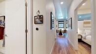 This single-floor residence showcases a thoughtfully designed interior that balances modern aesthetics with warm, inviting finishes throughout. Light hardwood flooring flows continuously from the entry hallway through the main living areas, creating a cohesive and airy feel. The welcoming corridor leads toward an open-concept dining and living area bathed in natural light from expansive black-framed floor-to-ceiling windows, which offer views of the surrounding urban landscape.

The kitchen is well-equipped with flat-front warm wood cabinetry extending to the ceiling, a marble-inspired tile backsplash, white quartz countertops, and a full suite of stainless steel appliances including a gas range and dishwasher. A central island provides additional prep and casual dining space.

The living area is generously proportioned, featuring a wall of gridded windows that flood the room with daylight. Two bathrooms serve the residence: one with a soaking tub and marble-tiled surround, the other with a sleek walk-in shower and an extended double vanity with warm wood cabinetry. Bedrooms are comfortably scaled, each with sliding closet doors and hardwood flooring, maintaining the home's clean, contemporary character throughout.