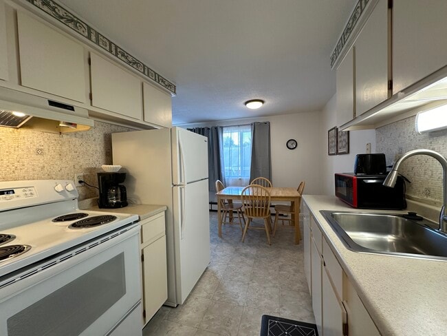 Full kitchen with large sized refrigerator, four burner stove and all dining & cookware - Avalon Apartments