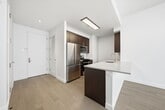 This contemporary 1030 square foot apartment offers a spacious and well-designed living experience. The property boasts four bedrooms, including a primary bedroom of 160 square feet, and three full bathrooms. The single-floor layout maximizes space efficiency and flow.

The interior is characterized by a clean, modern aesthetic with crisp white walls and warm wooden flooring throughout. Large windows in the bedrooms and living areas flood the space with natural light, creating a bright and airy atmosphere. The bathrooms feature a combination of white subway tiles and stylish patterned flooring, with modern fixtures and glass shower enclosures.

The kitchen is a highlight, showcasing dark wood cabinetry contrasted against white countertops and stainless steel appliances. A peninsula separates the kitchen from the living area, perfect for casual dining or entertaining. The open-concept design seamlessly integrates the kitchen with the living and dining spaces, ideal for modern lifestyles.

Storage is well-considered, with two dedicated closet spaces and built-in shelving in the bedrooms. The apartment also includes practical amenities such as in-unit climate control systems. Located in New York, this apartment combines urban convenience with contemporary comfort, offering a turnkey living solution in the heart of the city.