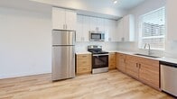 Located at 527 40th St in South Ogden, Utah, this thoughtfully designed one-bedroom, two-bathroom residence spans three floors, offering a well-organized layout with a clean, contemporary aesthetic. Light-toned luxury vinyl plank flooring flows through the main living areas, complemented by crisp white walls and abundant natural light throughout.

The kitchen is a standout feature, showcasing a two-tone design with warm wood lower cabinetry paired against sleek white upper cabinets and white quartz countertops. Stainless steel appliances — including a refrigerator, range, microwave, and dishwasher — complete the functional and stylish cooking space.

Both bathrooms reflect the same modern sensibility, featuring warm wood vanities topped with white stone countertops, large mirrors, and light hardwood-style flooring. One bathroom includes a full soaking tub with shelved surround, while the other offers a clean, minimalist vanity setup.

The generously sized primary bedroom is bathed in natural light through dual windows with views of the surrounding neighborhood. It connects directly to a bathroom and features plush neutral carpeting. An adjacent walk-in closet with wrap-around hanging rods and a natural light window provides ample storage.

Staircases connect all three levels, with the entry level serving as a welcoming transition into this well-appointed home.