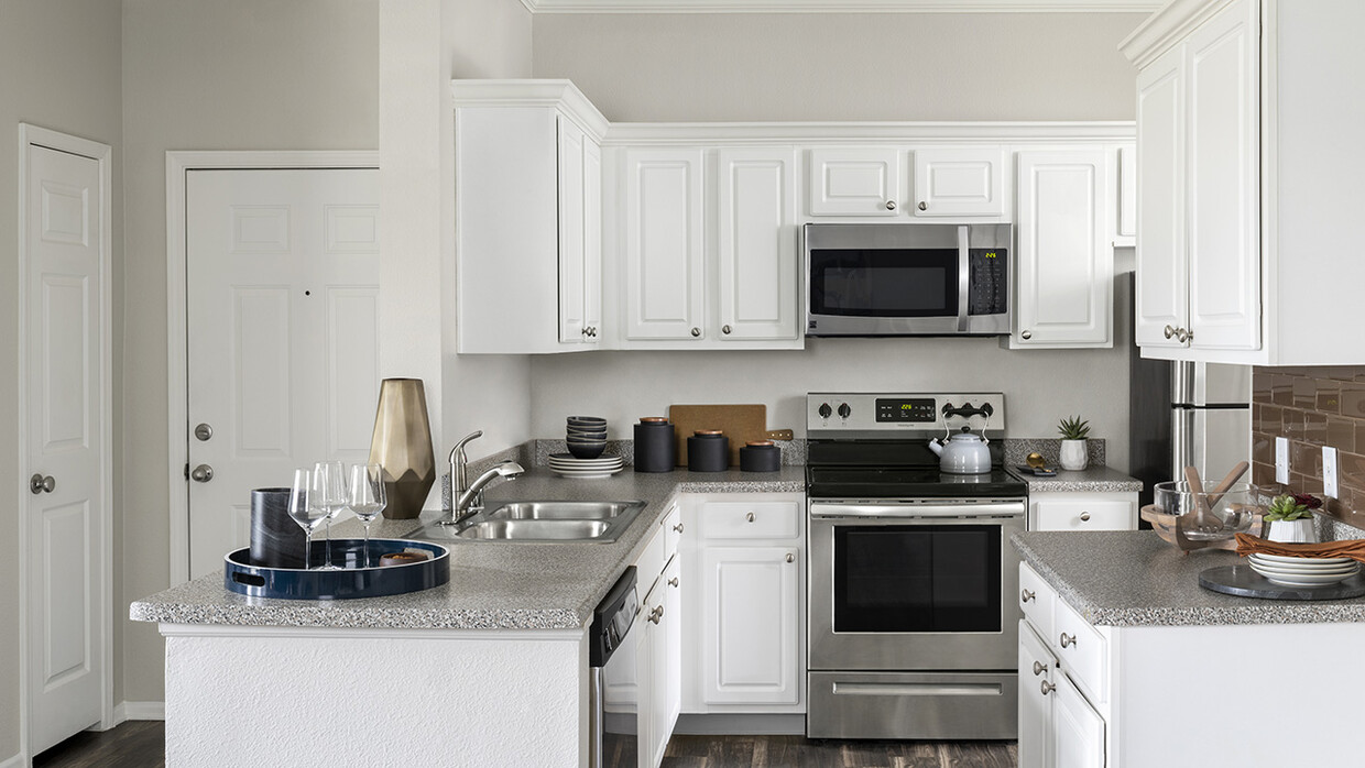 Cocina del apartamento con electrodomésticos de acero inoxidable, encimeras de granito y pisos de madera. - Sagebrook