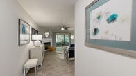 This single-floor, 2-bedroom, 2-bathroom residence offers a comfortable and cohesive layout designed for everyday living. The living room serves as the heart of the home, featuring wood-style flooring, a ceiling fan, and a white tile fireplace as a focal point. Sliding glass doors open to an outdoor patio, framing views of lush greenery and filling the space with natural light. Adjacent to the living room, the dining area accommodates a full dining table and benefits from large windows with views of mature trees, creating a bright and inviting atmosphere. The kitchen is outfitted with white shaker-style cabinetry, granite countertops, and stainless steel appliances, including a dishwasher and range, with an open pass-through that connects seamlessly to the dining and living areas. The primary bedroom is a generously sized retreat with ample natural light from a large window, while the second bedroom offers a cozy, versatile space with its own closet. Both bathrooms feature granite vanity countertops, white cabinetry, and tiled shower surrounds. Throughout the home, consistent wood-style flooring, neutral wall tones, and three closets provide both style and practicality. A hallway connects the private sleeping quarters to the main living areas, completing this well-organized floor plan.