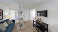 This single-floor residence offers a thoughtfully designed layout with distinct living spaces, each finished with practical yet attractive details. The living room serves as the centerpiece of the home, distinguished by its vaulted ceiling with exposed white-painted wood beam detailing that adds architectural character and a sense of openness. Soft carpeting, a large window with vertical blinds allowing ample natural light, and a wall-mounted television setup make this space both stylish and functional.

Adjacent to the living area, the dining space features wood-look flooring, a ceiling fan, and direct proximity to the kitchen, creating a seamless flow for everyday living and entertaining. The galley-style kitchen is equipped with white cabinetry offering generous storage, granite-look countertops, a double basin sink, and white appliances including a full-size refrigerator.

The bedroom is generously proportioned, featuring plush carpeting, a textured ceiling, and a large window that invites natural light. A sliding closet provides practical storage. The full bathroom includes a tub-shower combination, a single vanity with granite-look countertops, a large mirror, white cabinetry, and wood-look flooring, presenting a clean and functional design throughout.