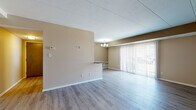 Located at 5292 Clubhouse Dr in North Olmsted, Ohio, this single-floor unit offers a practical and well-maintained layout with a cohesive neutral color palette throughout. The open living and dining area is finished with light-toned laminate wood flooring and features a chandelier overhead, a pass-through counter connecting to the kitchen, and a large sliding glass door fitted with vertical blinds that allows natural light to fill the space.

The kitchen is equipped with dark espresso cabinetry, granite-style countertops, a stainless steel sink, and a peninsula that provides additional prep and seating space. A chandelier above the adjacent dining area adds a finished touch to the combined kitchen and dining zone.

The bedrooms are carpeted and feature generous closet space, with bifold closet doors providing easy access to built-in hanging rods. Windows with horizontal blinds allow for natural light and outdoor views. An additional room with laminate flooring offers flexible use as an office or utility space.

The bathroom is notably updated, showcasing dark cabinetry with a granite-style countertop, a wide vanity mirror, recessed lighting, wood-look flooring, and a tiled tub and shower surround. Clean white trim throughout the unit ties all areas together for a consistent, polished appearance.