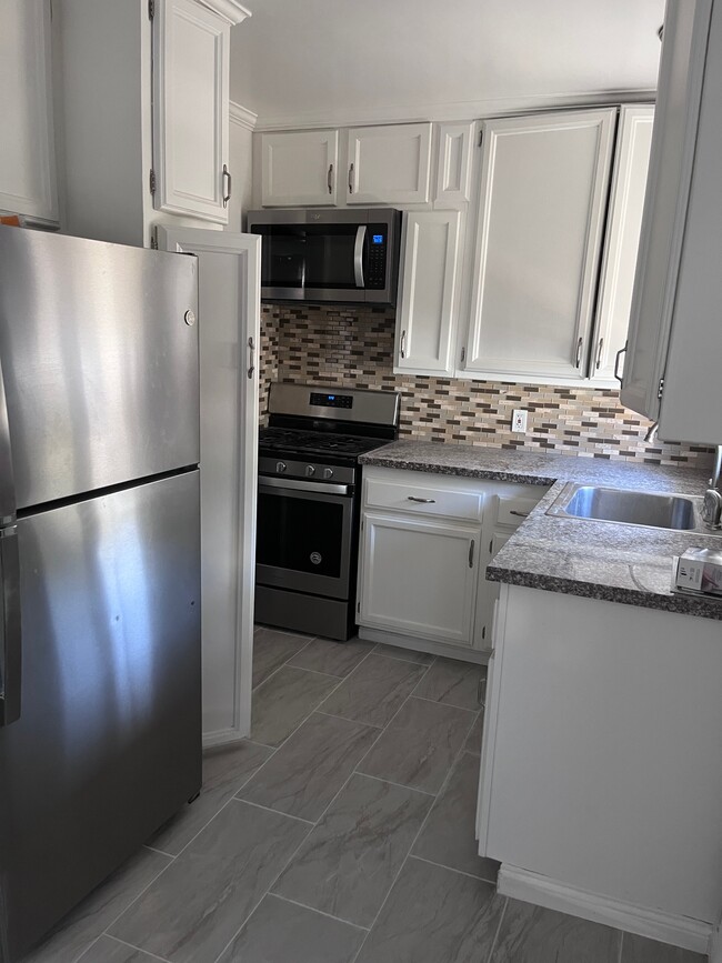 Kitchen with stainless steel appliances, granite countertops and new ceramic floor. - 11346 Califa St