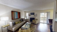 Located in the Bent Tree Forest area of Dallas, Texas, this single-story residence offers a well-organized layout designed for comfortable everyday living. The living room serves as the heart of the home, featuring rich hardwood flooring, a wood-burning fireplace with a white surround and mounted flat-screen TV above, and a sliding glass door that opens to a private outdoor balcony. Natural light filters in through multiple windows, creating a bright and welcoming ambiance. Adjacent to the living area is an intimate dining space, also with balcony access and hardwood floors, ideal for casual meals. The galley-style kitchen is outfitted with warm wood cabinetry, granite-look countertops, a double sink, and black appliances, providing efficient functionality. A dedicated bedroom offers plush carpeting, a ceiling fan, and natural light through blinds. A flexible room serves as a home office or secondary bedroom, complete with carpet, a ceiling fan, and ample wall space. The bathroom features a tiled tub-shower combination, wood-look flooring, and granite-look vanity countertops. An in-unit laundry area with a full-size washer and dryer adds everyday convenience. Throughout, textured ceilings and neutral tones create a cohesive, functional living environment.