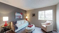 Located at 1075 Weybridge Rd in the desirable Columbus, Ohio 43220 area, this single-floor home offers a comfortable and well-appointed living environment. The living area serves as the heart of the space, showcasing a warm and modern aesthetic with a neutral color palette of soft grays and taupe tones across the walls and carpet. A large window floods the room with natural light, offering views of the surrounding mature trees and neighborhood streetscape, enhancing the sense of openness. The textured ceiling adds a classic architectural detail that complements the clean lines of the room. The space is designed for both relaxation and conversation, with thoughtful layout and tasteful décor accents including framed artwork that adds pops of color against the muted backdrop. The carpeted flooring contributes to the cozy, inviting ambiance throughout. Overall, this single-story home presents a well-maintained, move-in-ready living space with a balanced blend of comfort and contemporary style, situated in a established Columbus neighborhood.