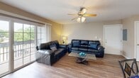 Located at 1601 E Florida Ave in Urbana, IL, this well-appointed unit offers three bedrooms, three full bathrooms, and a thoughtfully designed single-floor layout. The open-concept living and kitchen area serves as the heart of the home, where hardwood-style flooring flows throughout. The kitchen features light wood cabinetry, a granite-style breakfast bar, recessed lighting, and black appliances, including a side-by-side refrigerator and electric range. The adjoining living room is bright and welcoming, highlighted by a ceiling fan with light fixture, sliding glass doors that open to a private balcony, and ample natural light. Each of the three bedrooms is carpeted and features large windows that bring in natural light, with dedicated closets providing generous storage. The primary bedroom is comfortably sized with its own adjoining closet and bathroom access. All three bathrooms share a consistent, clean design with light wood vanities, white countertops, framed mirrors, and hardwood-style flooring. The neutral warm-toned walls and cohesive finishes throughout create a comfortable and functional living environment well-suited for shared or family occupancy.