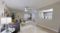 This single-floor residence offers a thoughtfully designed layout with a seamless flow between living and functional spaces. The expansive open-plan living area is anchored by light wood-style flooring, neutral gray walls, and a ceiling fan with integrated lighting. The space extends naturally into a designated home office or study nook, separated by a partial wall with a pass-through opening to the kitchen, allowing for both connectivity and definition between areas.

The kitchen is well-appointed with gray cabinetry, white quartz countertops, a subway tile backsplash, stainless steel appliances including a refrigerator, range, and over-the-range microwave, and a deep undermount sink — combining modern aesthetics with practical functionality.

The primary bedroom is generously sized, featuring light flooring, a window with blinds for natural light, and access to a walk-in closet. A secondary bedroom provides a clean, neutral space with the same cohesive finishes found throughout.

The bathroom is finished with large-format gray tile surrounding the tub-shower combination, a floating gray vanity with a white countertop, and wood-style flooring, presenting a clean, contemporary design. A dedicated dining area rounds out this well-organized and stylishly presented residence.
