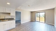 Located at 8185 Palmetto Ave in Fontana, CA, this single-floor residence offers four bedrooms and two bathrooms within a efficiently designed layout. The living area features light-toned wood-style vinyl flooring and neutral warm-beige walls throughout, creating a clean, cohesive aesthetic. A textured ceiling adds character to the main living and bedroom spaces. Sliding glass doors in both the living room and primary bedroom open to a private balcony with outdoor views of surrounding greenery, filling the interior with natural light.

The kitchen is outfitted with white cabinetry, dark granite-style countertops, and stainless steel appliances including a refrigerator, range, and microwave. It connects seamlessly to the living area, supporting an open flow. The four bedrooms are finished consistently with the same flooring and neutral palette; the primary bedroom includes direct balcony access, while additional bedrooms feature windows with tree-lined views. Two closets provide dedicated storage throughout.

The two bathrooms are functionally appointed — one features a full tub/shower combo with chrome fixtures, and the second includes a shower and grab bar. Both maintain the same light flooring found throughout the home, ensuring a unified and clean finish.