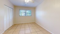 Located at 3545 30th Ave N in Saint Petersburg, Florida, this efficient one-bedroom, one-bathroom unit offers a well-organized single-floor layout. Light-colored ceramic tile flooring runs consistently throughout every room, creating a cohesive, easy-to-maintain interior well-suited to Florida's climate.

The open living area is bright and airy, with neutral cream-toned walls and a textured ceiling. A hallway connects the main living space to the bedroom and bathroom, providing a clear and functional flow. The galley-style kitchen is positioned along one side of the unit and features white cabinetry, a white electric range, and a full-size refrigerator, along with a sink and tile backsplash — offering practical utility in a compact footprint.

The bedroom is a comfortable size, fitted with a ceiling fan, a window that brings in natural light and views of surrounding greenery, and direct access to the hallway. The bathroom includes a full bathtub with white tile surround extending to the walls, and a frosted glass window that allows natural light while maintaining privacy.

Throughout the unit, consistent HVAC venting and wall-mounted heating units ensure year-round comfort. The clean, minimal design and durable finishes make this Saint Petersburg unit a straightforward and functional living space.