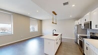 Located in the heart of downtown Tulsa at 501 S Cincinnati Ave, this well-appointed 2-bedroom, 2-bathroom unit offers a thoughtfully designed single-level floor plan with modern finishes throughout. The open-concept kitchen and living area serves as the centerpiece of the space, featuring a white kitchen island with a striking black matte faucet and sink, white shaker cabinetry with black hardware, quartz countertops, a geometric patterned tile backsplash, and stainless steel appliances. A gold-toned pendant light fixture above the island adds a warm, contemporary accent. The living area offers generous open space with large windows allowing natural light to fill the room, offering views of the surrounding cityscape. Both bedrooms are carpeted and feature tray ceilings with ceiling fans, creating a comfortable and refined retreat. The primary bedroom is a well-proportioned space with ample room for furnishings. The bathrooms are finished with clean white vanities, black hardware, and a standout walk-in shower clad in large-format dark gray tile with a hexagonal mosaic tile floor and a matte black showerhead. Neutral tones and recessed lighting throughout the unit create a cohesive, modern aesthetic.
