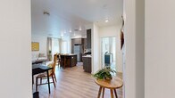 This thoughtfully designed single-story residence offers a seamless open-concept layout that connects the main living areas with ease. Light wood-look flooring flows throughout, anchoring the bright, white-walled interiors and contributing to a clean, contemporary aesthetic.

The kitchen is a standout feature, showcasing dark wood-grain cabinetry extending to the ceiling, a classic white subway tile backsplash, light quartz countertops, and a full suite of stainless steel appliances including a refrigerator, gas range, microwave, and dishwasher. A central island with bar seating provides an ideal space for casual dining and meal prep.

The open living area is bright and inviting, benefiting from natural light through large windows dressed with linen drapes. The space comfortably accommodates a full living room arrangement.

Two bedrooms offer restful retreats, each featuring light-filled windows, wood-look flooring, and ceiling fans. The primary bedroom includes access to a dedicated en-suite bathroom, which features large-format tile in the walk-in shower with glass enclosure, wood-look flooring, and a vanity with ample storage. A walk-in closet is accessible directly from the bathroom. The second bedroom is equally bright and well-proportioned, making it versatile for various uses.