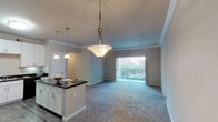 This single-story residence offers a thoughtfully designed layout across two bedrooms and two full bathrooms. The open-concept kitchen is a standout feature, equipped with white shaker-style cabinetry, dark granite countertops, black appliances including a range, microwave, and dishwasher, and wood-style vinyl flooring. A spacious island with pendant lighting above provides additional prep space and serves as a natural transition into the living area.

The living room is carpeted and bathed in natural light, featuring crown molding and a sliding glass door that opens to a private balcony with outdoor views. Both bedrooms are generously sized with plush carpet, ceiling fans, and vertical-blind windows that allow ample natural light.

Each bathroom features wood-style vinyl flooring, white cabinetry, and a full tub-shower combination with tile accents. A dedicated in-unit laundry area accommodates a full-size side-by-side washer and dryer. Crown molding and consistent finishes throughout the space contribute to a cohesive, well-maintained aesthetic suited for comfortable everyday living.