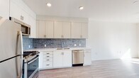 Located in the Silver Lake neighborhood of Los Angeles, this single-floor unit at 1363 Colton St offers a clean, modern aesthetic throughout. The open-concept kitchen is a standout feature, outfitted with crisp white cabinetry extending to the ceiling for ample storage, light quartz countertops, and a striking blue-gray subway tile backsplash that adds a refined contrast. Stainless steel appliances — including a gas range, built-in microwave, dishwasher, and refrigerator — complete the fully equipped cooking space. Light wood-look flooring runs seamlessly through the kitchen and into the open living area, creating a bright, cohesive feel. The bedroom is generously proportioned, bathed in natural light through a large window that frames views of the surrounding neighborhood greenery, and features the same warm wood-tone flooring for continuity. The bathroom is finished with large-format neutral tiles, a frameless glass-enclosed walk-in shower with a herringbone mosaic tile floor, and a clean, minimalist design. Recessed lighting throughout the unit maintains a bright and airy ambiance, while the overall white palette and modern finishes give the space a fresh, contemporary character well-suited to urban Los Angeles living.