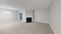 Located at 6029 Flat Rock Rd in Columbus, GA, this well-appointed single-story home offers two bedrooms and two full bathrooms across a comfortable and functional floor plan. The spacious living room serves as the heart of the home, featuring a classic white-mantled fireplace, neutral carpet flooring, a textured ceiling, and a sliding glass door that brings in natural light. The kitchen is a standout feature, equipped with white cabinetry, granite-look countertops, stainless steel appliances including a refrigerator and dishwasher, and light wood-look flooring. A breakfast bar-style peninsula connects the kitchen to the living area, creating an open and accessible layout. The primary bedroom is generously sized, highlighted by a ceiling fan, a window with blinds, and direct access to a closet. The second bedroom mirrors this design with its own ceiling fan and window. Both bathrooms are finished with granite-top vanities, wood-look tile flooring, and tub-shower combinations with curved curtain rods and brushed nickel fixtures. Additional storage is provided by two closets, and a hallway connects all rooms efficiently. Neutral tones throughout give the home a clean, move-in ready appearance.