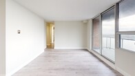 This 2-bedroom, 1-bathroom single-floor residence offers a clean, modern aesthetic throughout, characterized by a neutral color palette, light wood-look flooring, and crisp white trim that unify each room seamlessly. The entry hallway welcomes residents with a bright, open feel, leading naturally into the rest of the home. The living room is a generous, light-filled space anchored by a large sliding glass door that invites natural light and provides access to an outdoor area, with views of the surrounding brick exterior architecture. The galley-style kitchen is thoughtfully designed with white shaker cabinetry, brushed nickel hardware, light quartz countertops, a stainless steel sink, and a full suite of stainless steel appliances including a refrigerator, electric range, and over-the-range microwave — all finished with a classic white tile backsplash. The primary bedroom offers a comfortable footprint with a full-width sliding panel closet for ample storage. The second bedroom similarly features a sliding panel closet and easy hallway access. The bathroom is finished with a full-size soaking tub and shower, surrounded by clean white rectangular wall tiles and chrome fixtures. Three hallways connect the spaces efficiently, completing this well-organized and move-in-ready home.