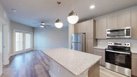 Located at 7551 Narcoossee Rd in Orlando, FL, this thoughtfully designed one-bedroom, one-bathroom unit offers a modern and efficient layout. The open-concept living and kitchen area serves as the heart of the space, featuring light wood-tone cabinetry, a granite-topped center island with pendant lighting overhead, and a full suite of stainless steel appliances including a refrigerator, range, microwave, and dishwasher. Light hardwood-style flooring flows throughout the main living areas, complemented by neutral walls and recessed lighting that create a bright, welcoming ambiance. The living area offers access to a private outdoor space through elegant French doors, with a ceiling fan adding comfort to the room. The bedroom is carpeted for warmth and comfort, with a ceiling fan, a natural light window, and easy access to a dedicated closet. The bathroom is appointed with a wood-grain vanity, granite countertop, a framed mirror, and a tiled shower. Clean lines, contemporary finishes, and a cohesive neutral palette make this a polished and functional space well-suited for modern living in the heart of Orlando.