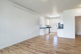 This single-story home offers a practical and clean layout across three bedrooms and one full bathroom. Light hardwood flooring runs throughout the interior, lending warmth and continuity to each room. The open living area flows naturally toward the galley-style kitchen, which is outfitted with sleek white cabinetry, dark stone countertops, black appliances including a refrigerator, range, and built-in microwave, and recessed lighting overhead. A door at the end of the kitchen provides direct exterior access, enhancing convenience.

Each bedroom features the same hardwood flooring and is bright with natural light from large windows that frame neighborhood views. The primary bedroom includes a double-door closet offering ample storage. The full bathroom is finished in white with a tub-shower combination, a dark-topped vanity, and matching hardwood flooring.

Outside, the property includes an attached garage with a concrete driveway, a well-maintained front lawn with a young tree, and a generous backyard with a metal-roofed storage shed and mature trees lining the rear. The exterior features neutral siding in keeping with the surrounding neighborhood. Overall, the home presents a clean, functional, and move-in ready environment.