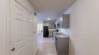 Located at 414 NW Third St in Bentonville, Arkansas, this single-story home offers three bedrooms, three full bathrooms, and a functional layout designed for comfortable living. The kitchen is outfitted with gray cabinetry, granite-look countertops, a double-basin sink, and black appliances, opening directly into the living and dining area. Light wood-style flooring runs throughout the main living spaces, while the living room benefits from a ceiling fan and a large window that fills the room with natural light and outdoor views. Each bedroom features plush carpeting, individual windows for natural light, and dedicated closets—including spacious walk-in closets equipped with wire shelving systems for ample storage. The primary bedroom is a well-proportioned private retreat. All three bathrooms share a consistent design language, featuring gray vanities with granite-look countertops and tub-shower combinations with built-in shelving. A connecting hallway links all rooms efficiently across the single floor. The home's neutral color palette and clean finishes create a bright, move-in-ready atmosphere suited for a variety of living arrangements.
