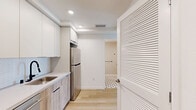 Located at 738 S Normandie Ave in Los Angeles, this thoughtfully designed studio offers a clean, modern aesthetic across a single floor. Light hardwood flooring flows throughout, complementing the bright white walls and recessed lighting that create an airy, open atmosphere.

The kitchen is efficiently laid out with sleek flat-panel cabinetry in white and warm wood tones, white quartz countertops, a herringbone tile backsplash, and a full suite of stainless steel appliances including a range, dishwasher, microwave, and refrigerator. The open-plan living area is bathed in natural light from large windows and a sliding glass door that opens to a private balcony, offering views of the surrounding Los Angeles neighborhood.

The bathroom features distinctive black-and-white hexagonal tile flooring, a clean vanity with warm wood cabinetry, and matte black hardware accents that add a modern touch. A dedicated closet and in-unit laundry area add to the practicality of the space. The overall design balances compact, efficient living with contemporary finishes, making it a well-appointed residence in the heart of Los Angeles.