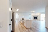 Located in Gretna, Nebraska, this well-appointed 2-bedroom, 2-bathroom residence offers a thoughtfully designed single-floor layout with modern finishes and a bright, welcoming atmosphere. The open-concept kitchen and living area serves as the heart of the home, showcasing white shaker cabinetry, quartz countertops, a large center island with a black matte faucet and sink, and stainless steel appliances including a refrigerator, range, and microwave. Light wood-look flooring flows throughout the main living areas, complementing the clean, neutral palette. The living room is anchored by a striking corner fireplace clad in stacked stone tile with a rustic wood mantel, and a sliding glass door opens to a private balcony with neighborhood views. Both bedrooms feature plush carpet, ceiling fans, and walk-in closets with built-in shelving. The bathrooms are finished with white cabinetry, quartz countertops, and matte black hardware, with one offering a tub-shower combination. A dedicated laundry room accommodates full-size washer and dryer units. A skylight in the kitchen area adds an extra touch of natural light, enhancing the overall airy and modern ambiance of this move-in-ready home.
