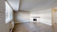 Located at 4701 E Mississippi Ave in Glendale, CO, this two-bedroom, one-bathroom residence offers a well-organized single-floor layout with a thoughtful mix of finishes throughout. The open living and dining area is anchored by a striking full-brick wood-burning fireplace, creating a warm focal point for the space. Light hardwood-style flooring runs throughout the main living areas, complemented by natural light from multiple windows fitted with blinds. The kitchen is efficiently designed with warm wood cabinetry, white quartz countertops, a chevron-pattern tile backsplash, a black matte faucet, and stainless steel appliances. Track lighting illuminates the kitchen, adding a modern touch. Both bedrooms feature plush carpeting and windows that bring in natural light and outdoor views. The primary bedroom includes a large sliding-door closet, providing ample storage. A second closet is also available within the unit for additional storage needs. The hallway connects the living spaces to the bedrooms and bathroom in a straightforward, functional layout. Baseboard heating is present throughout, and a wall-unit air conditioner ensures year-round comfort. The overall aesthetic is clean and contemporary with classic residential character.