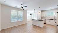 Located at 2403 Mall Dr in North Charleston, SC, this single-story residence offers 2 bedrooms and 3 bathrooms within a well-designed, efficiently organized floor plan. The interior is defined by a clean, modern aesthetic, with crisp white walls, light wood-look flooring in the main living areas, and an abundance of natural light streaming through large windows fitted with white blinds.

The open-concept living and dining area flows seamlessly into the kitchen, which serves as the centerpiece of the home. The kitchen features white shaker-style cabinetry extending to the ceiling, dark countertops, a subway tile backsplash, stainless steel appliances, and a central island with additional counter seating. Globe pendant lights add a contemporary touch overhead. A separate dining nook with large windows and a pendant light connects directly to an exterior door, enhancing the sense of openness.

A bright hallway lined with recessed lighting connects the bedrooms and bathrooms. Both bedrooms are carpeted, with natural light provided by large windows and ceiling fans for comfort. The primary bedroom includes a walk-in closet outfitted with wire shelving systems. The bathrooms feature dark-topped vanities and framed mirrors. A dedicated laundry room houses a full-size washer and dryer with overhead shelving, adding everyday convenience to this well-appointed residence.