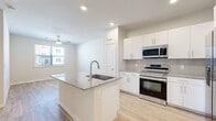 Located in Spring, TX, this well-designed one-bedroom, one-bathroom residence offers a thoughtfully organized single-floor layout that maximizes every square foot. The open-concept kitchen is a standout feature, showcasing a granite-topped center island with an undermount sink, crisp white shaker cabinetry, a tiled backsplash, and a full suite of stainless steel appliances including a refrigerator with ice maker, electric range, microwave, and dishwasher. A stacked washer and dryer unit is conveniently integrated near the kitchen area. Light wood-tone flooring flows seamlessly throughout the entire residence, creating a cohesive and airy feel. The living area opens naturally from the kitchen, providing a comfortable and versatile space. The bedroom is well-proportioned, featuring a ceiling fan, neutral walls, and a window that brings in natural light with exterior views. The full bathroom is finished with marble-style tiled shower and tub surround, white cabinetry, granite countertops, and wood-look flooring. A dedicated walk-in closet with wire shelving provides ample storage. Ceiling fans are present in multiple rooms, enhancing comfort throughout this clean, modern residence.