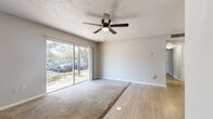 This 2-bedroom, 2-bathroom single-story home in Orlando, FL offers a practical and well-organized layout. The open living area features a combination of plush carpet and wood-look flooring, a ceiling fan with light fixture, and a large sliding glass door that fills the space with natural light and provides outdoor views of the surrounding greenery. The kitchen is outfitted with white shaker-style cabinetry, light stone-look countertops, and stainless steel appliances including a refrigerator, dishwasher, and range, all set over wood-look flooring for easy maintenance. Both bedrooms are carpeted and feature windows that bring in natural light. The primary bedroom includes a closet with sliding doors, while the second bedroom is served by a nearby hallway closet. A dedicated hallway connects the bedrooms to the two full bathrooms, each featuring a tiled tub-shower combination, wood-look flooring, and clean white fixtures. Textured ceilings are present throughout the home. The layout is efficient and functional, with a centrally located hallway providing clear separation between the living areas and bedrooms, making this a well-suited home for comfortable everyday living in Orlando.