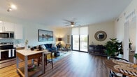 Located at SW 98th Court in Palmetto Bay, Florida, this single-floor unit offers a thoughtfully designed open-concept layout that seamlessly connects the kitchen, dining, and living areas. Wood-style flooring runs throughout, contributing a warm, cohesive aesthetic to the entire space.

The kitchen is outfitted with stainless steel appliances—including a side-by-side refrigerator with ice maker, dishwasher, and built-in microwave—complemented by two-tone cabinetry featuring sleek white upper cabinets and warm wood-finished lower cabinets, along with light countertops and track lighting overhead.

The open living area is bright and welcoming, anchored by a ceiling fan with integrated lighting. Large sliding glass doors lead to a private balcony, allowing abundant natural light to fill the room while offering views of the surrounding greenery. Roller shades provide adjustable light control throughout.

The bedroom is a comfortable retreat featuring a ceiling fan, a window with natural light, and ample room for furnishings. The bathroom includes a full tub-shower combination with tile surround, wood-look tile flooring, and clean, neutral finishes that maintain a consistent modern aesthetic throughout the unit.