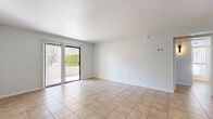 Located at 400 N 96th Ave in Tolleson, Arizona, this single-story, one-bedroom, one-bathroom unit offers a practical and well-organized layout. Consistent tile flooring runs throughout the entire space, providing a cohesive and easy-to-maintain finish.

The open-concept living room is generously proportioned, bathed in natural light from a sliding glass door that opens to an outdoor patio. Vertical blinds offer privacy and light control. The space flows seamlessly into the kitchen area via a pass-through counter opening.

The kitchen is well-appointed with white cabinetry featuring black hardware, light quartz-style countertops, and a full suite of stainless steel appliances including an electric range, over-the-range microwave, refrigerator, and dishwasher. A recessed tray ceiling adds a subtle architectural detail overhead.

The bedroom is a comfortable, well-lit room with a window overlooking greenery, tile flooring, and direct access to a dedicated closet and the hallway. The full bathroom includes a combined tub and shower unit with clean white surrounds, warm-toned tile flooring, and a curved shower rod. A hallway connects all rooms efficiently, completing the thoughtful layout of this compact yet functional Tolleson residence.