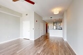 Located in the heart of downtown Orlando at 111 East Washington Street, this modern single-floor unit offers a thoughtfully designed open-concept layout that maximizes both function and style. The living and dining areas flow seamlessly together, finished with warm hardwood-style flooring and neutral-toned walls that create a bright, inviting atmosphere. A ceiling fan overhead adds comfort, while floor-to-ceiling glass windows and sliding doors flood the space with natural light and frame impressive panoramic views of the Orlando skyline — a standout feature of this high-rise residence.

The kitchen is well-appointed with crisp white cabinetry, dark granite countertops, a classic tile backsplash, and a full suite of stainless steel appliances, including a range, microwave, dishwasher, and refrigerator. Pendant lighting above the kitchen peninsula adds a contemporary touch, while tile flooring grounds the culinary space cleanly. An adjacent utility and laundry area, along with a dedicated closet, round out the functional offerings of this efficiently planned unit. The overall design balances modern urban living with practical amenities, making it a compelling option in one of Orlando's most vibrant downtown locations.