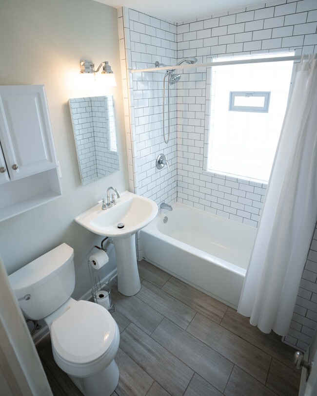 Bathroom is white and bright with ceramic tile floor and subway tiled shower and deep bathtub - 5029 N Bay Ridge Ave