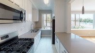 Located in the heart of Los Angeles at 6200 W 3rd St, this single-floor residence offers a well-designed layout with a clean, neutral aesthetic throughout. The open-concept living area is a standout feature, showcasing warm parquet hardwood flooring in a classic basket-weave pattern, crown molding, and a large picture window that floods the space with abundant natural light while offering views of the surrounding neighborhood greenery.

The galley-style kitchen is thoughtfully appointed with white shaker cabinetry, gray quartz countertops, a subway tile backsplash, stainless steel appliances including a gas range, microwave, and refrigerator, and a window that brings in additional natural light. An in-unit washer is also conveniently accessible off the kitchen area.

The bedrooms are carpeted and generously proportioned, each with windows providing natural light. One bedroom features a spacious walk-in closet with dual shelving and hanging rods, offering ample storage. Additional bedrooms also include closet space.

The bathroom is finished in a crisp white palette with a pedestal sink, a combination tub and shower with white tile surround, light vinyl plank flooring, and mirrored storage. The overall ambiance of the residence is bright, clean, and functional, well-suited to the vibrant Los Angeles lifestyle.
