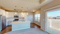 This single-floor residence offers a thoughtfully designed open-concept layout that seamlessly connects the kitchen, dining, and living areas. The kitchen is a standout feature, showcasing white shaker-style cabinetry extending to the ceiling, a large center island with a built-in sink and light countertops, stainless steel appliances including a refrigerator, microwave, and range, and pendant lighting complemented by a track lighting system. Wood-look flooring anchors the kitchen and dining zone, while plush carpeting flows throughout the living and bedroom areas.

The living room is bathed in natural light through a sliding glass door that opens to a private balcony, offering outdoor views. A tile-surround fireplace with a white mantel serves as a focal point, while a tray ceiling adds architectural depth to the space.

The bedrooms are generously proportioned, featuring tray ceilings, neutral carpet, and natural light from well-placed windows. The primary bedroom includes a ceiling fan and access to a private en-suite bathroom equipped with a walk-in glass-door shower and wood-look flooring. A second full bathroom features a shower-tub combination and a white vanity. Throughout, the warm neutral palette and clean finishes create a bright, cohesive, and welcoming ambiance.