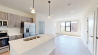 Located at 31 Holland Ave in Albany, NY, this single-floor, 3-bedroom, 2-bathroom residence offers a thoughtfully designed layout with modern finishes throughout. The open-concept kitchen and living area serves as the heart of the home, where light wood flooring, recessed lighting, and large black-framed windows fill the space with natural light and neighborhood views. A balcony access door in the living area extends the space outdoors.

The kitchen is well-appointed with taupe shaker-style cabinetry, white quartz countertops, stainless steel appliances—including a French door refrigerator, range, microwave, and dishwasher—and a center island with a double sink illuminated by pendant lighting.

The three bedrooms feature plush carpeting and ample closet space, including a spacious walk-in closet with wire shelving in the primary bedroom, which also benefits from generous natural light. Additional bedrooms include built-in closet storage. Two bathrooms feature light wood-tone flooring and clean, contemporary fixtures. The overall aesthetic is bright and neutral, creating a versatile, move-in-ready living environment.