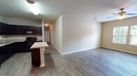 Located in Jacksonville, FL (32205), this single-floor home offers a practical and comfortable layout with consistent finishes throughout. The spacious living area is finished with rich, dark wood-style flooring and features a ceiling fan with lighting, neutral warm-toned walls, and windows fitted with blinds that invite natural light. A textured ceiling adds subtle character to the space.

The open-concept design connects the living area directly to the kitchen and dining space. The kitchen is well-equipped with dark espresso cabinetry, black appliances including a refrigerator, electric range, built-in microwave, and dishwasher, all complemented by light granite-style countertops. A peninsula island provides additional prep space and casual seating. A pendant light fixture anchors the dining area nearby.

Two full bathrooms serve the home. Both feature dark vanity cabinetry with granite-style countertops and illuminated mirrors. One bathroom includes a tiled tub-and-shower combination, while the other offers a walk-in style configuration. Wood-look tile flooring runs throughout the bathrooms.

A dedicated laundry room houses a full-size washer and dryer along with a water heater, providing added convenience. The floor plan, as seen in the 3D model, reveals multiple private rooms and a well-organized interior layout suited for everyday living.