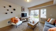Located at 802 South Garfield Road in Airway Heights, WA, this single-floor apartment offers a comfortable and functional layout across several well-defined living spaces. The living room is bright and inviting, featuring large sliding glass doors and an adjacent window that usher in natural light and provide views of the outdoors. Plush wall-to-wall carpeting adds warmth to the space. The galley-style kitchen is efficiently designed with warm wood cabinetry, ample counter space, a double-basin sink, a dishwasher, and black appliances including a range and refrigerator, all set on tile flooring. Adjacent to the kitchen, a cozy dining nook accommodates a four-seat table beneath a pendant light, making it an ideal spot for meals. Two bedrooms feature carpeted floors and closets, with one bedroom offering a large window with outdoor views. The unit includes two bathrooms, both with tile flooring, wood vanities, and light countertops; the larger bathroom features a tub-shower combination and an expansive mirror. A hallway connects the private spaces, completing the thoughtful floor plan of this Airway Heights residence.