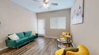 This single-story residence offers a comfortable and thoughtfully designed layout, encompassing two bedrooms, two bathrooms, a kitchen, a living room, and a closet. The living room serves as the heart of the home, featuring durable wood-look plank flooring, a ceiling fan with light fixture, and large windows fitted with blinds that allow for ample natural light. The space flows seamlessly into a secondary sitting area, which also benefits from the same flooring and direct access to the front entry door.

The kitchen is equipped with gray shaker-style cabinetry, light granite-look countertops, a decorative tile backsplash, and black appliances including a range, microwave, and refrigerator, all set over matching wood-look flooring.

Both bedrooms feature plush carpet flooring and windows with blinds. The primary bedroom is a generously sized retreat with its own ceiling fan, while the secondary bedroom offers a comfortable and bright environment.

The two bathrooms echo the home's modern aesthetic, each featuring gray vanity cabinetry with marble-look countertops, wood-look tile flooring, and well-lit vanity mirrors. One bathroom includes a shower-tub combination. Neutral warm-beige walls throughout the home create a cohesive and inviting ambiance.