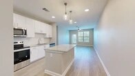 Located at 1880 SW 43rd St in Gainesville, FL, this single-floor, 3-bedroom, 2-bathroom home offers a thoughtfully designed layout with contemporary finishes throughout. The open-concept kitchen and living area serves as the heart of the home, featuring a granite-topped center island, crisp white shaker cabinetry extending to the ceiling, a classic subway tile backsplash, and a full suite of stainless steel appliances including a refrigerator, electric range, microwave, and dishwasher. Pendant lighting and recessed fixtures illuminate the kitchen, which flows seamlessly into the living room. The living area is bright and airy, benefiting from large windows with blinds, a ceiling fan, and direct access to an outdoor area via a glass-paned door. Light wood-look flooring runs throughout the main living spaces, adding warmth and continuity. The three bedrooms are carpeted for comfort and receive generous natural light through large windows fitted with blinds. Ceiling fans are present in the bedrooms, and multiple rooms include access to closets, with at least one walk-in closet featuring wire shelving. The two bathrooms are finished with granite-topped white vanities, wood-look tile flooring, framed mirrors, and glass-enclosed showers. A hallway connects the private quarters, completing this clean and functional floor plan.