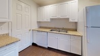 Located at 133A Connecticut Ave in Stamford, Connecticut, this two-floor residence offers a clean, functional layout with a straightforward and practical design. The interior is finished with neutral white and light gray walls throughout, accented by dark baseboards that provide a crisp contrast against the wall-to-wall carpeting found in the main living and bedroom areas.

The main level welcomes you through a distinctive green front door into a bright, open living area featuring dual windows that allow natural light to fill the space and offer views of the surrounding greenery. The kitchen is well-appointed with white cabinetry, granite-style countertops, a double-basin stainless steel sink, and a dishwasher, all set atop durable hardwood-style flooring. A bathroom on this level is finished in all white and includes a full soaking tub with shower, a wall-mounted sink, and a privacy window.

The upper level continues the same clean aesthetic, with multiple carpeted rooms that serve well as bedrooms or flexible-use spaces. Each room features ample wall space, standard windows fitted with white blinds for light control, and access points that create a connected flow throughout. A thermostat is conveniently located on the upper floor for climate control. The overall ambiance is bright, move-in ready, and well-suited for comfortable everyday living.