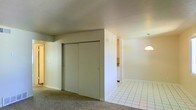 This single-floor residence offers a practical and straightforward layout designed for comfortable everyday living. The interior is characterized by a clear transition between distinct functional zones, each finished with different flooring materials that help define the spaces naturally.

The carpeted area serves as a bedroom or living space, featuring a set of full-panel sliding closet doors that provide generous storage capacity. The neutral-toned walls and smooth ceiling create a clean, understated backdrop throughout.

Adjacent to the carpeted zone, the space transitions to white square ceramic tile flooring, suggesting a kitchen or dining area. A classic pendant light fixture hangs overhead in this area, adding a focused point of illumination and a subtle decorative touch. The open passageway between the two areas allows for an easy flow through the layout.

Overall, the space maintains a simple, functional aesthetic with light-colored walls and standard residential finishes throughout. The absence of excess ornamentation keeps the environment clean and adaptable, making it well-suited for a variety of furnishing and décor styles. The single-floor plan ensures convenient accessibility across all areas of the residence.