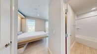 Located at 1116 W Carmen St in Tampa, FL, this compact and thoughtfully designed studio unit offers a smart, modern layout that maximizes every square foot. The space features light wood-tone flooring throughout, neutral warm-white walls, and recessed lighting that contribute to a bright and cohesive aesthetic.

The sleeping area is anchored by a built-in Murphy bed with an integrated wood-paneled surround and soft underlighting, providing both functionality and a clean, contemporary look. Two windows with horizontal blinds and a vertical blind panel allow ample natural light to filter in, with views of the surrounding Tampa neighborhood.

The kitchen is efficiently appointed with stainless steel appliances, including a full-size refrigerator, electric range with smooth cooktop, over-range microwave, and a deep single-basin stainless steel sink with a professional-style pull-down faucet. Light wood cabinetry and a white quartz-style countertop keep the kitchen feeling open and modern.

The bathroom is neatly finished with wood-look tile flooring, a full-size soaking tub with shower, a white tile surround, and a vanity with under-mount sink and wood-toned cabinetry. Recessed lighting provides clear, functional illumination throughout. This well-appointed studio is ideal for those seeking a streamlined, low-maintenance living space in a vibrant Tampa location.