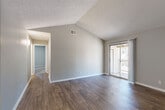 Located at 1557 Terrell Mill Rd SE in Marietta, GA, this 2-bedroom, 1-bathroom residence offers a well-designed single-floor layout with a variety of notable architectural features. The living room immediately stands out with its vaulted ceilings that lend a sense of openness and volume to the space. Rich, dark hardwood-style flooring runs throughout the main living areas, complementing the neutral gray walls and clean white trim. A sliding glass door leads directly from the living room to a private balcony, offering pleasant outdoor views of surrounding trees and bringing in abundant natural light.

The adjoining dining area transitions seamlessly from the living space, featuring lighter hardwood-style flooring and a pendant light fixture overhead. The galley-style kitchen is equipped with white cabinetry, a stainless steel refrigerator, a range, and ample counter space, all finished with wood-look flooring.

Both bedrooms are carpeted and feature textured ceilings, neutral walls, and windows with blinds that allow for natural light. The primary bedroom is generously sized and is supported by two closets, one of which is a walk-in closet with wire shelving and carpeted flooring. The full bathroom includes a vanity with white cabinetry, a tub-shower combination, and wood-look flooring, maintaining the clean, consistent aesthetic found throughout the home.